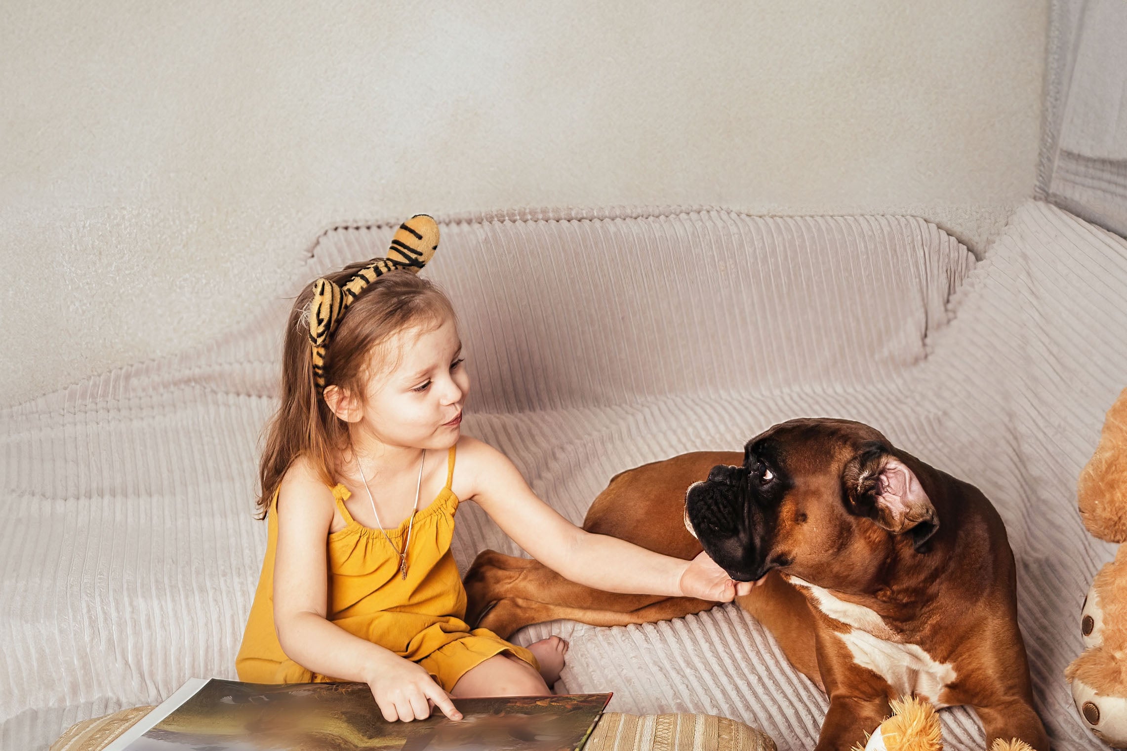 girl pointing to book and scratching dogs chin